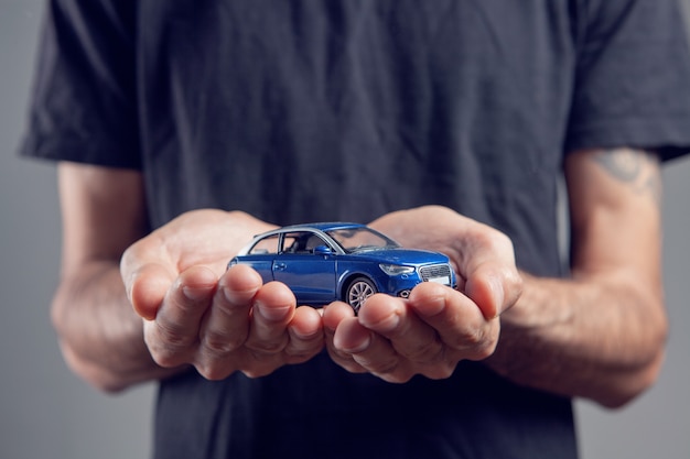 Un homme tenant une petite voiture dans ses mains