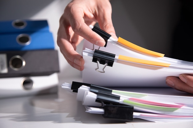 Homme tenant une pile de documents sur la table