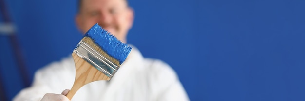 Homme tenant un pinceau avec gros plan de peinture bleue