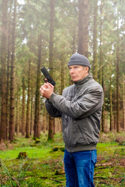 Homme tenant un pistolet à l'arrière-plan de la forêt