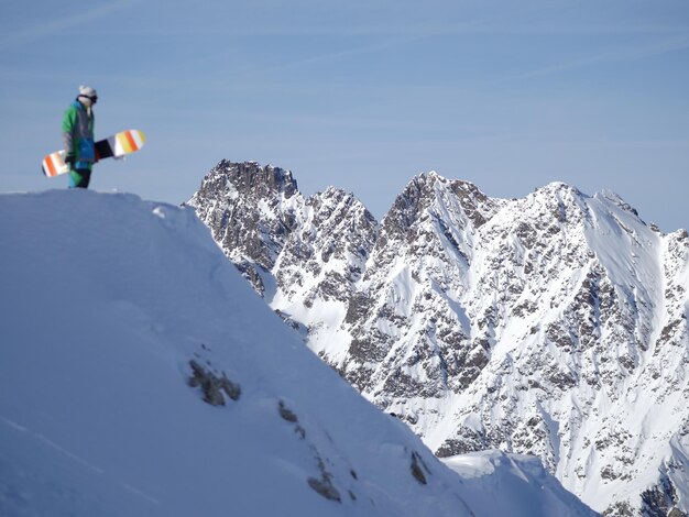 Un homme tenant une planche à neige sur un paysage