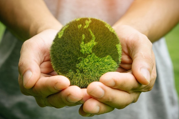 Photo l'homme tenant la planète dans les mains contre le fond vert du printemps le concept du jour de la terre la terre dans les mains.