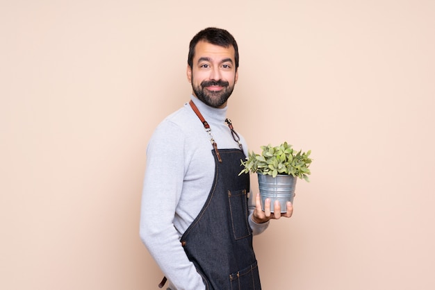 Homme tenant une plante sur fond isolé souriant