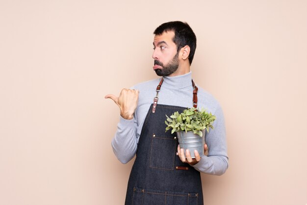 Homme tenant une plante malheureuse et pointant sur le côté