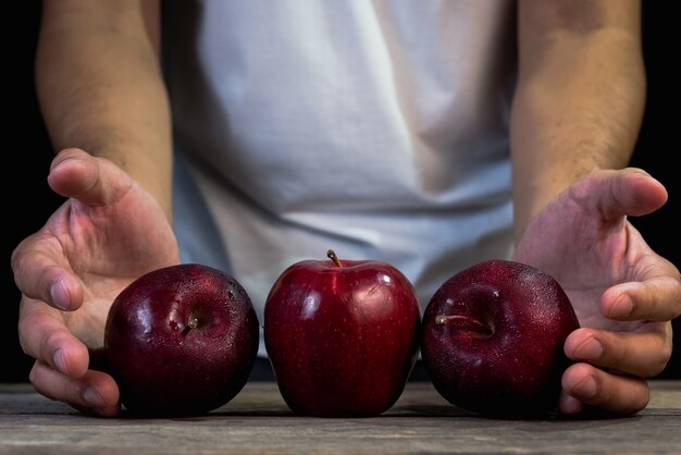 L&#39;homme tenant une pomme rouge sur une table en bois