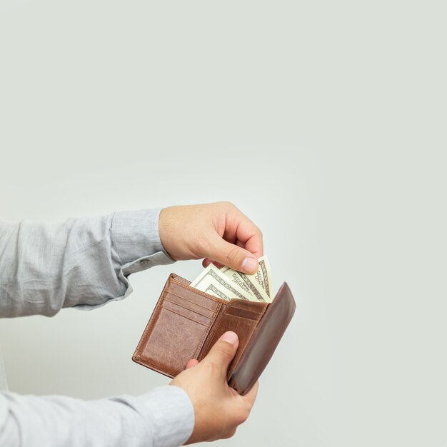 Homme tenant un portefeuille en cuir ouvert plein d'argent ou de billets en papier