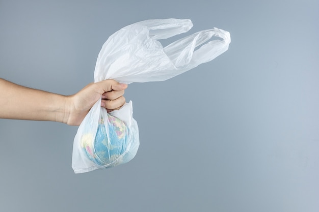 Homme tenant un sac en plastique et un globe à l'intérieur avec un espace de copie pour le texte. Protection de l'environnement, zéro déchet, réutilisable, ne dites pas de plastique, concept de la journée mondiale de l'environnement et du jour de la terre