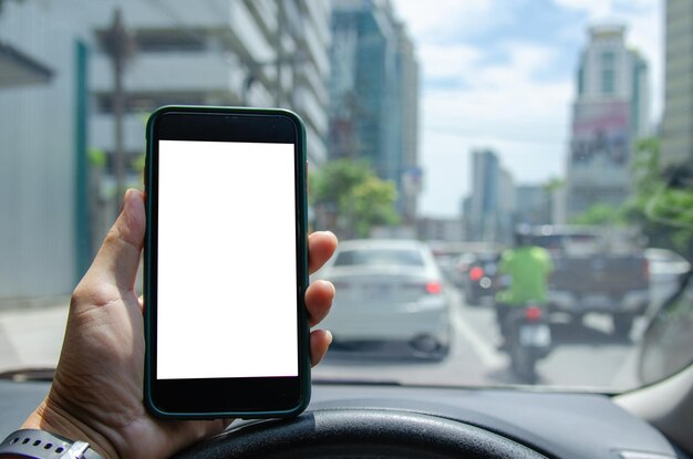 Homme tenant un smartphone mobile maquette écran blanc dans la voiture