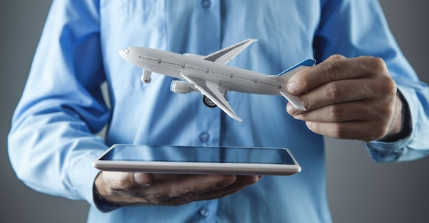 Homme tenant une tablette avec un avion jouet. Concept de voyage