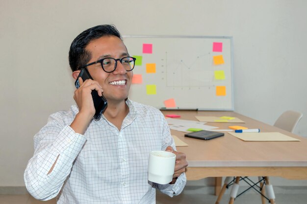 Un homme tenant une tasse et parlant au téléphone