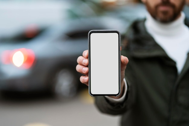 Homme tenant un téléphone avec un blanc sur le fond de la ville Place pour la publicité écran vide