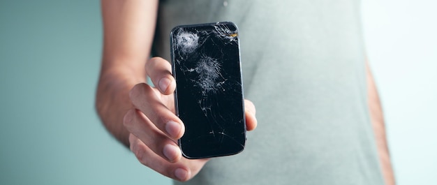 Un homme tenant un téléphone avec un écran cassé