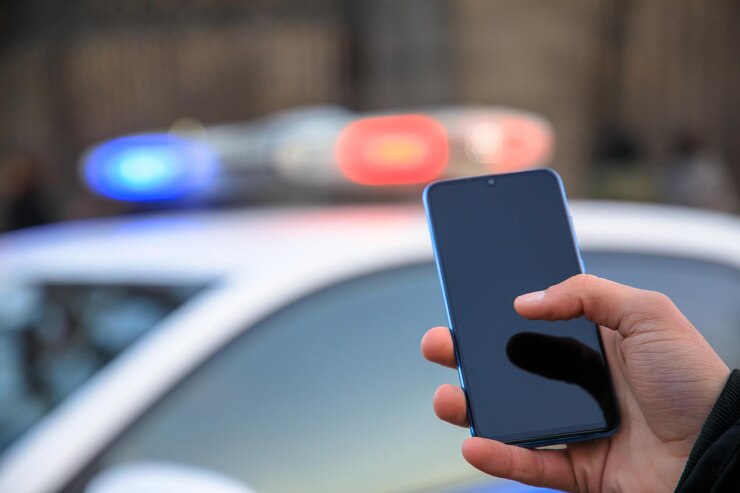 Homme tenant un téléphone avec une voiture de police