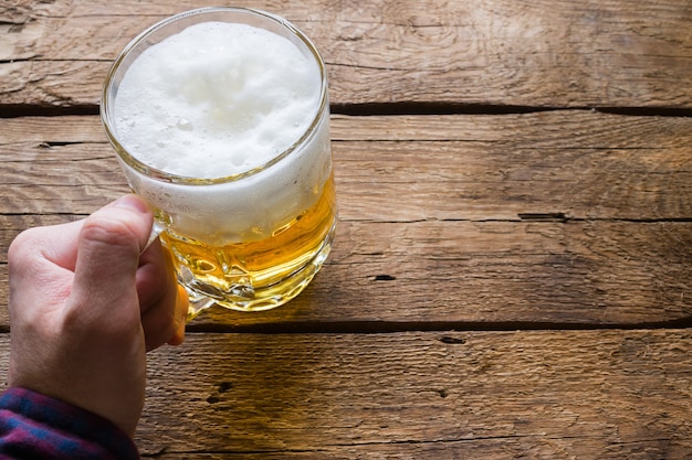 Homme tenant un verre de bière sur un fond en bois