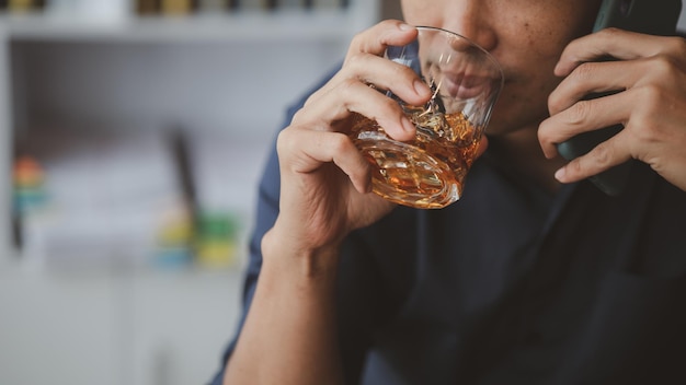 Homme tenant un verre de cognac, il boit du cognac dans un bar boire de l'alcool nuit à la capacité de conduire et peut nuire à la santé Le concept de la consommation d'alcool