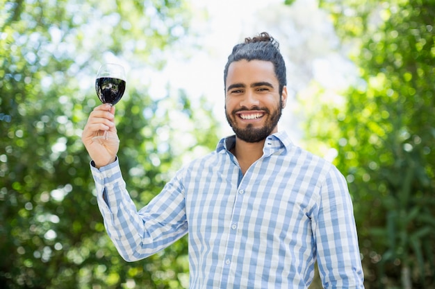 Homme tenant un verre de vin dans le parc