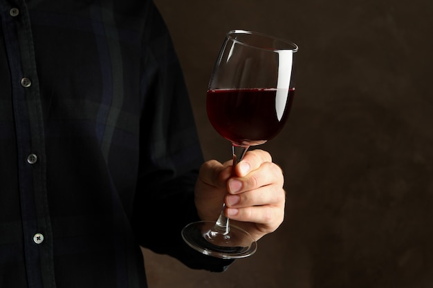 Homme tenant un verre de vin sur fond marron