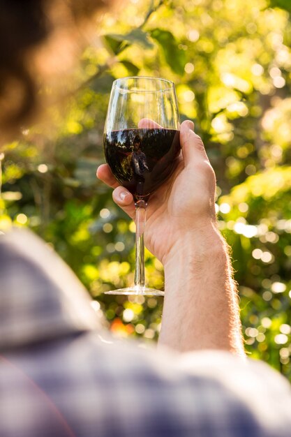 Homme tenant un verre de vin rouge dans le jardin