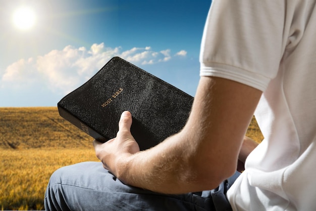 Homme tenant un vieux livre biblique sur fond