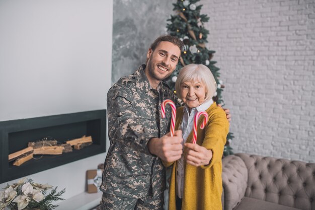 Homme en tenue de camouflage et sa maman se sentant heureuse