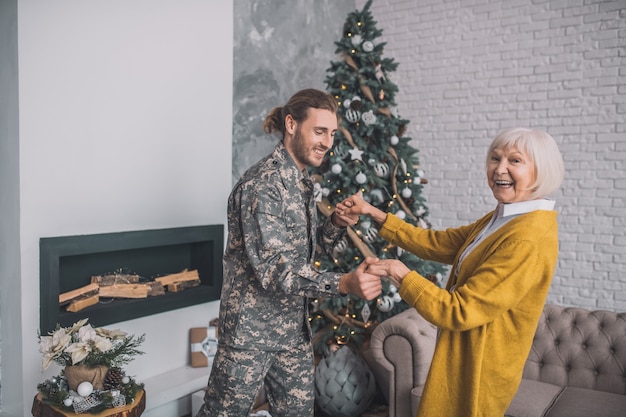 Homme en tenue de camouflage et sa maman se sentant heureuse