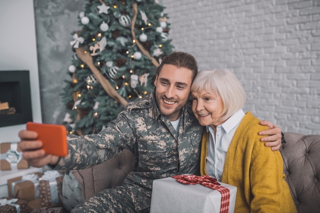 Homme en tenue de camouflage et sa maman se sentant heureuse