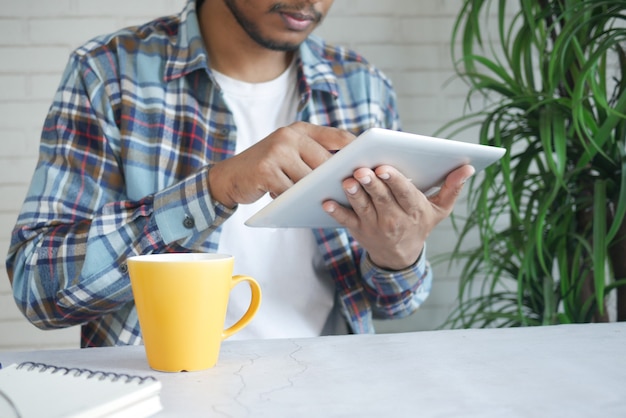 L'homme en tenue décontractée à l'aide de tablette numérique sur fond noir