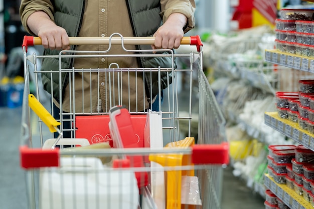 Homme en tenue décontractée poussant le caddie lors d'une visite au supermarché