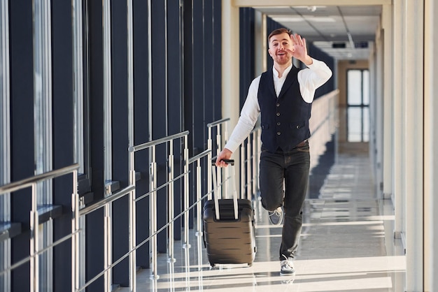 Un homme en tenue formelle et avec des bagages court vers l'avant et s'occupe d'un avion.