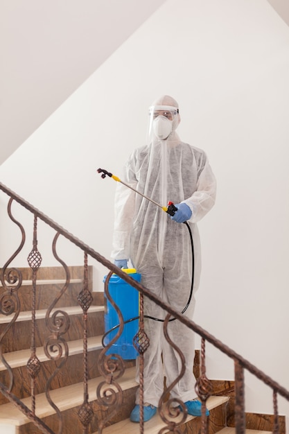 Homme en tenue de protection désinfectant le bâtiment contre la contamination par le coronavirus.