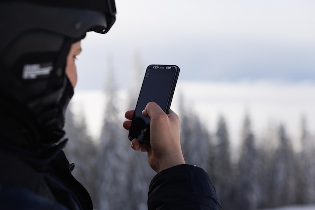 Un homme en tenue de ski avec un téléphone dans les mains.