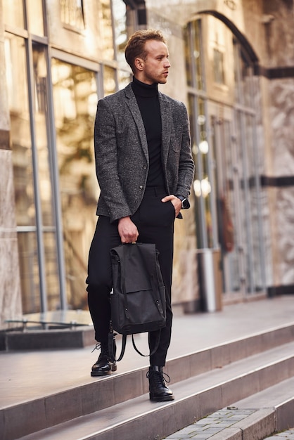 L'homme En Tenue De Soirée Élégante Et Avec Sac Est À L'extérieur Contre Un  Bâtiment Moderne. Banque D'Images et Photos Libres De Droits. Image  157645597