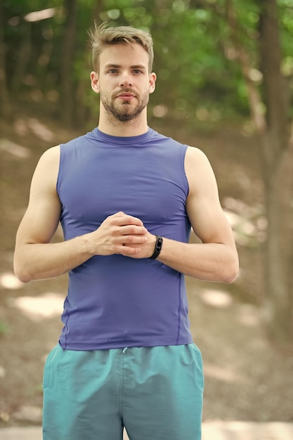 L'homme en tenue sportive a l'air confiant en plein air sur fond de nature Guy barbu corps musclé fier de sa forme sportive Corps musclé sportif prêt pour la course du matin Profitez du bien-être et d'un corps sain