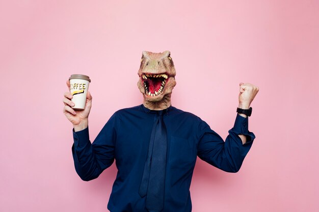 Homme à tête de dinosaure tenant une tasse de café