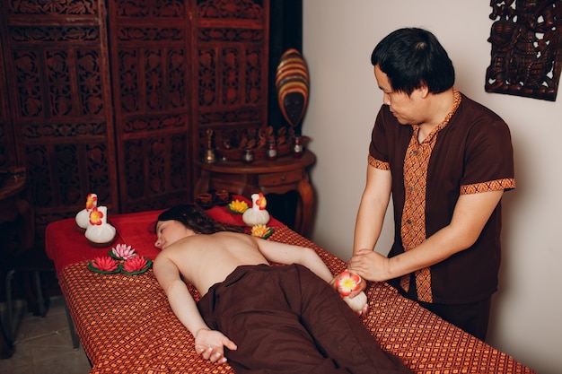 Homme thaïlandais faisant une procédure de massage thaïlandais classique à une jeune femme au salon de beauté spa