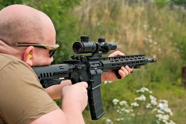 Un homme tient une arme automatique un homme regarde dans la vue d'une arme militaire