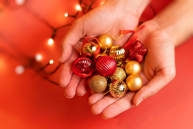 Un homme tient beaucoup de jouets de Noël rouges et or dans les mains un fond rouge Photo de haute qualité