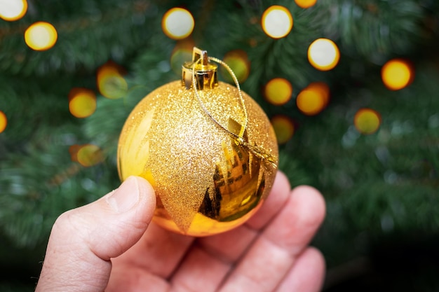 Un homme tient une boule décorative pour décorer un sapin de Noël