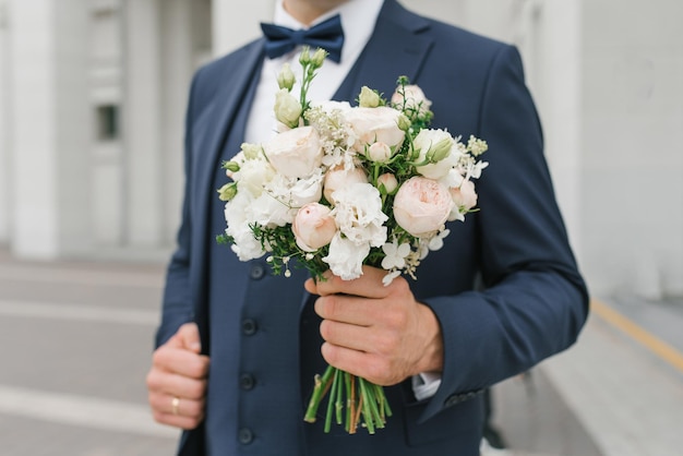 Un homme tient un bouquet de mariage dans ses mains Le concept de la Saint-Valentin et de l'amour Concept de mariage