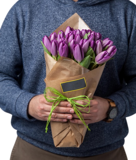 L'homme tient un bouquet de tulipes violettes liées à la Saint-Valentin