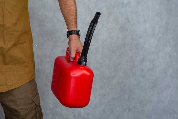 L'homme tient une bouteille de gaz en plastique rouge dans ses mains.