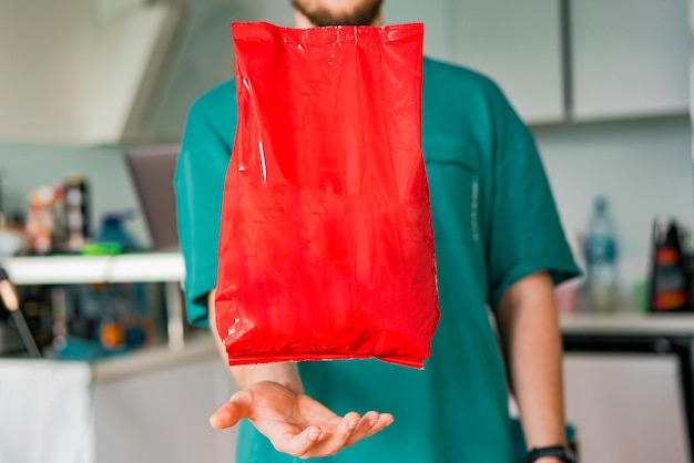 L'homme tient un bras sous la boîte en plastique rouge isolée. Achats. Acheteur. Accueil. Cuisine. Vide. Vierge