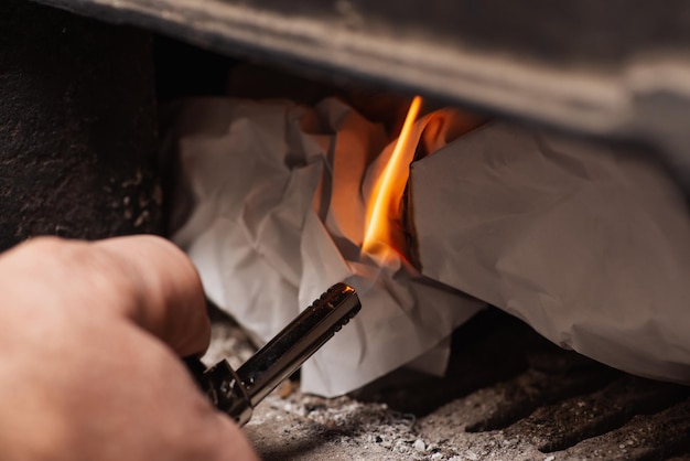 L'homme tient un briquet à gaz et fait un feu dans la chaudière à combustible solide Chauffage chaleur hiver concept de carburant renouvelable