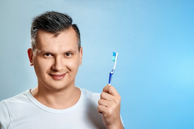 Un homme tient une brosse à dents et se brosse les dents.