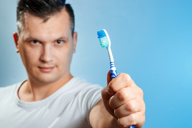 Un homme tient une brosse à dents et se brosse les dents.