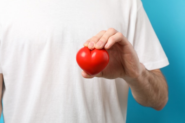 L'homme tient le coeur sur fond bleu