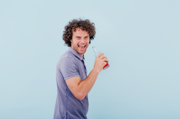 homme tient dans sa main bouteille de boisson