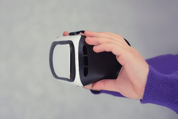 L'homme tient dans ses mains des lunettes pour la réalité virtuelle et la vidéo à 360 degrés. Casque VR pour smartphone sur fond clair.