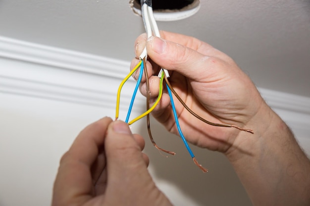 L'homme tient du ruban adhésif dans ses mains Isolant électrique pour ampoule Travaux de réparation d'entretien dans l'appartement Restauration à l'intérieur