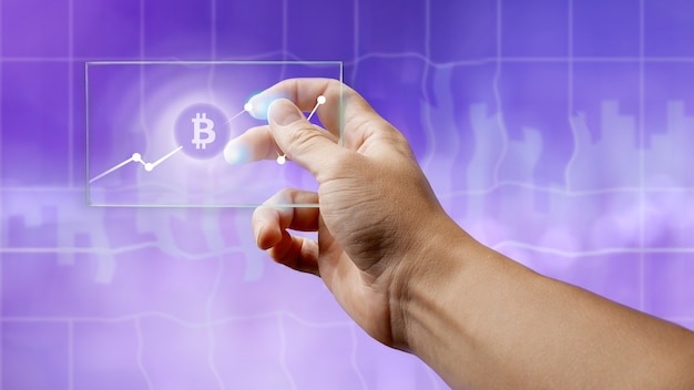 Un homme tient un écran en verre avec un symbole bitcoin et un graphique de devise crypto